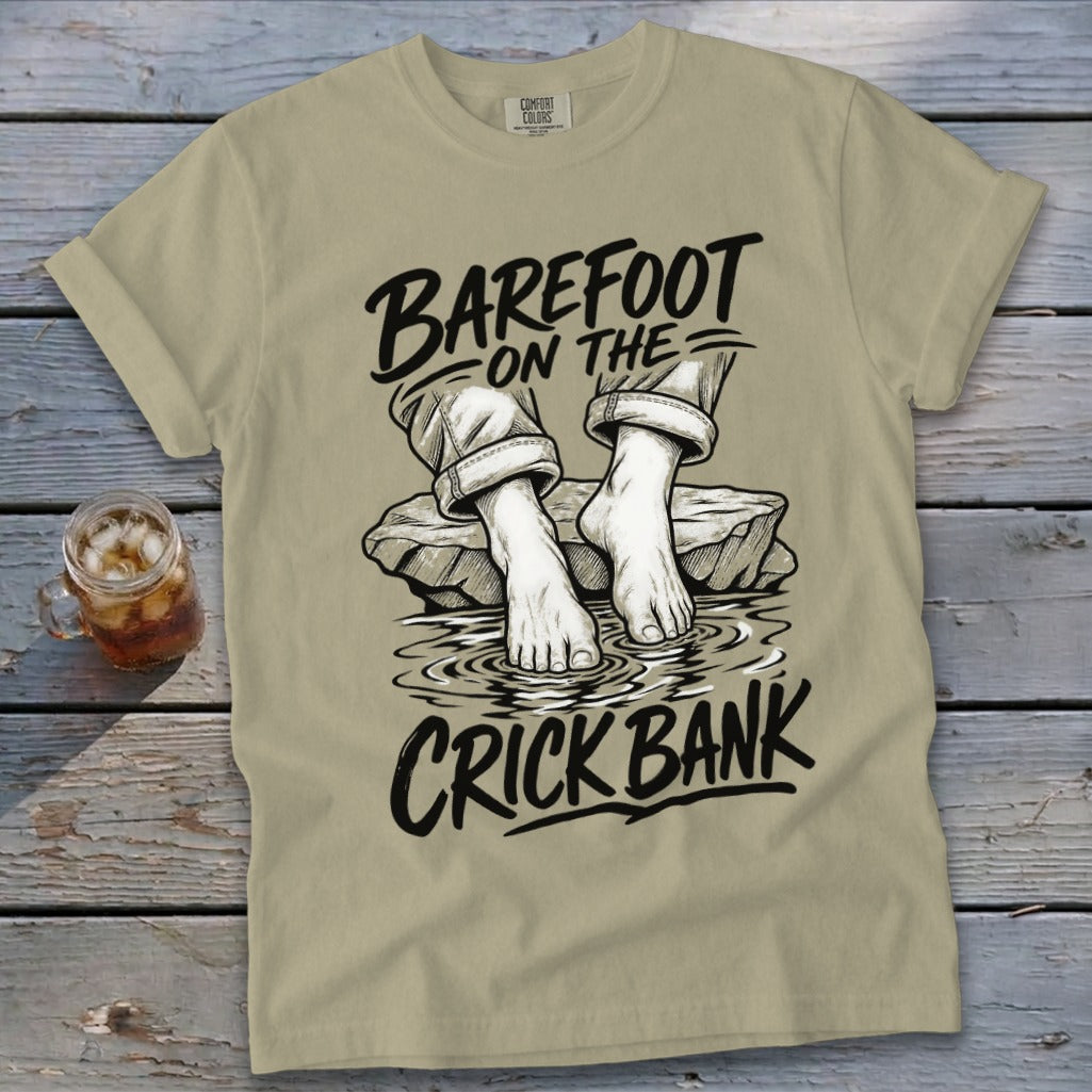 Khaki t-shirt with "Barefoot on the Crick Bank" graphic of bare feet on rocks in water.
