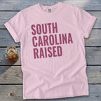 Pink t-shirt with "SOUTH CAROLINA RAISED" in maroon text.