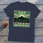 Dark blue t-shirt with a green graphic featuring mountains and the text "BORN IN THE HOLLER RAISED ON THE RIDGE".