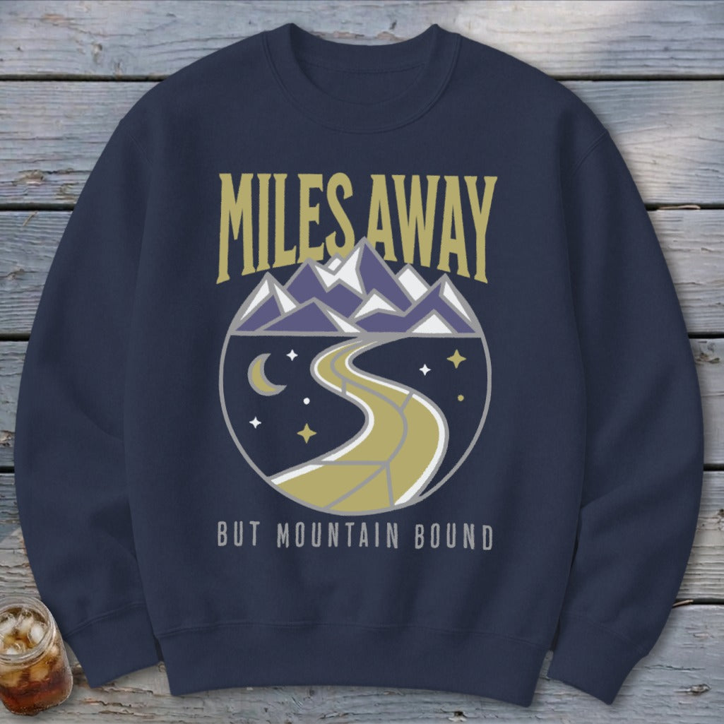 Dark blue sweatshirt with "Miles Away But Mountain Bound" text and mountain landscape design.