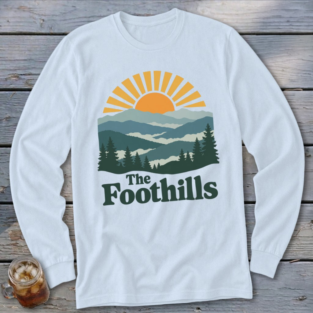 White long-sleeve shirt with "The Foothills" and mountain sunset graphic.