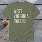 Olive green t-shirt with "West Virginia Raised" printed in pale yellow text.