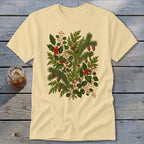 Light yellow t-shirt with a detailed illustration of pine branches, holly, and pinecones.