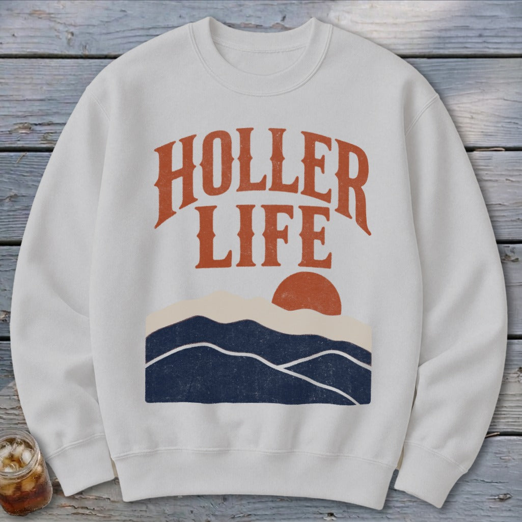 A light gray crewneck sweatshirt features the text "HOLLER LIFE" above a graphic of mountains and a sun.