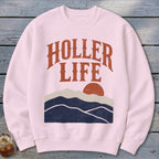 Light pink crewneck sweatshirt featuring the text HOLLER LIFE above a sunset mountain graphic.