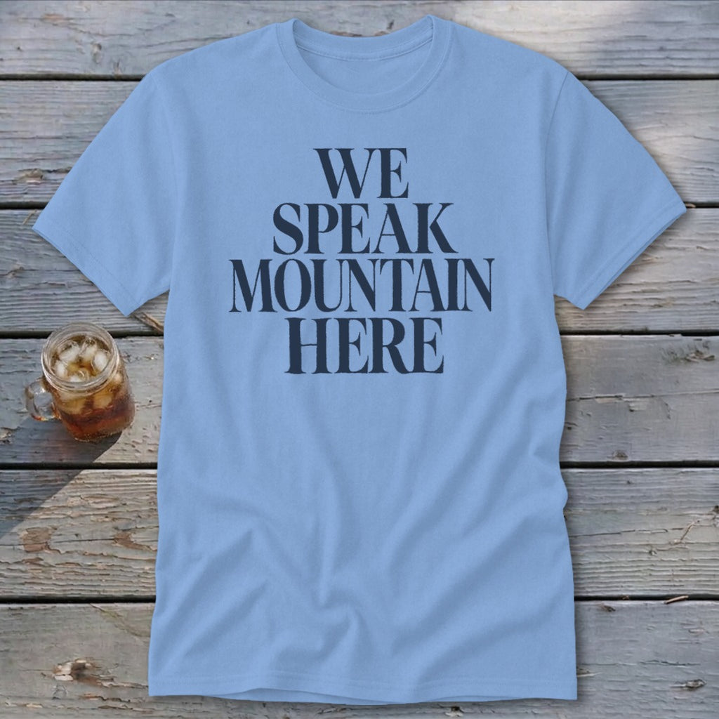 Light blue t-shirt with "WE SPEAK MOUNTAIN HERE" in dark grey text.