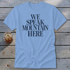 Light blue t-shirt with "WE SPEAK MOUNTAIN HERE" in dark grey text.