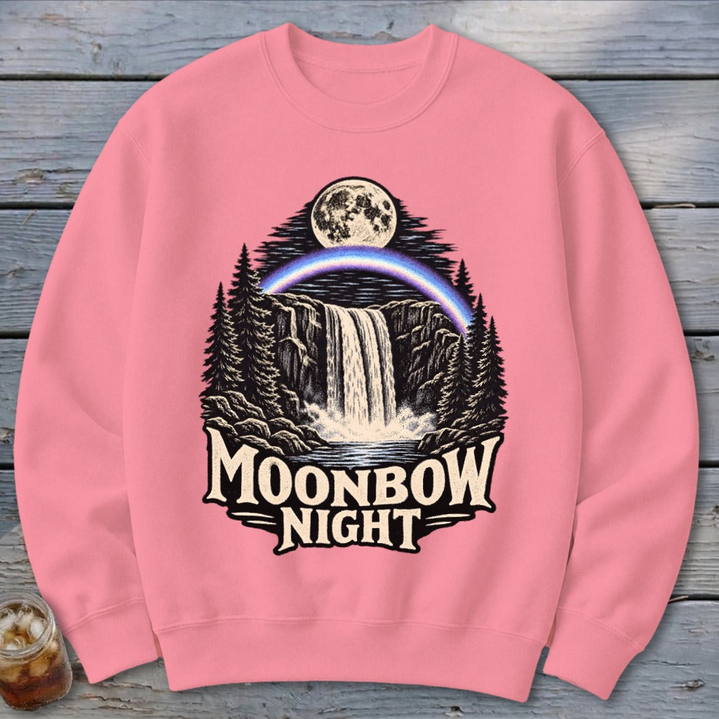 Pink sweatshirt with Moonbow Night waterfall, moon, and rainbow graphic.