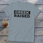 Gray t-shirt with black text that reads "CREEK RAISED".