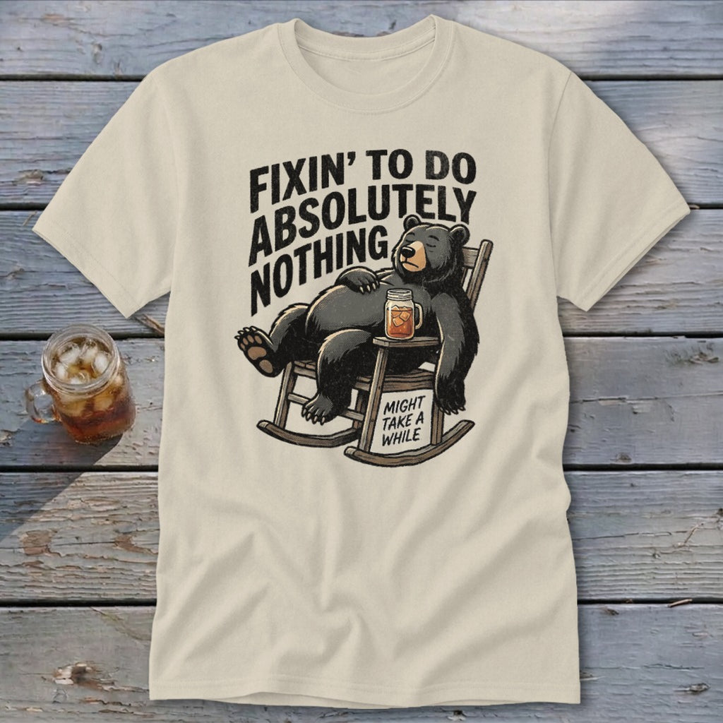 Cream t-shirt featuring a graphic of a bear lounging in a rocking chair with text reading "Fixin' to do absolutely nothing".