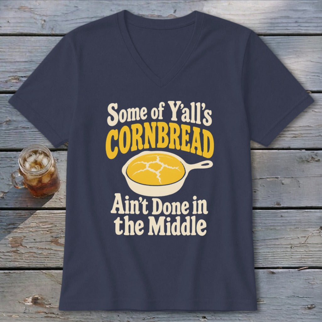 A dark blue V-neck t-shirt with text reading "Some of Y'all's CORNBREAD Ain't Done in the Middle" and a graphic of cornbread in a skillet.
