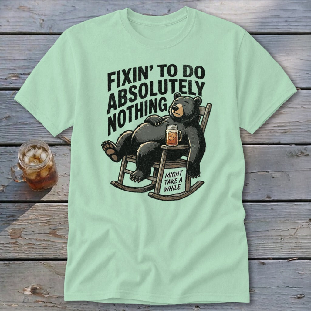 A light green t-shirt with a cartoon bear relaxing in a rocking chair with a drink.