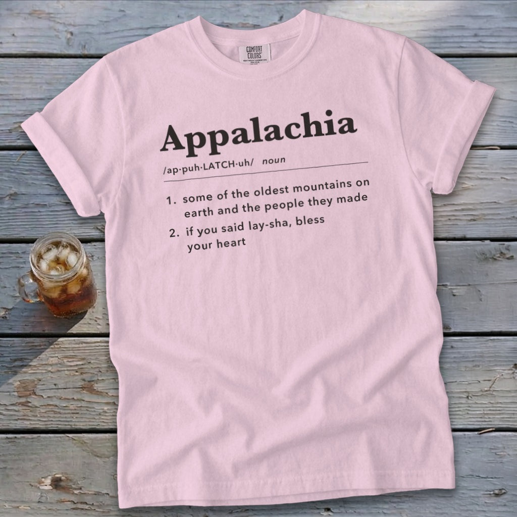Light pink t-shirt featuring dictionary-style text defining Appalachia, laid flat on a rustic wooden surface.