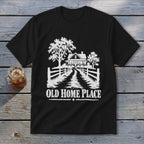Black t-shirt with white graphic of a house, trees, fence, and text OLD HOME PLACE.