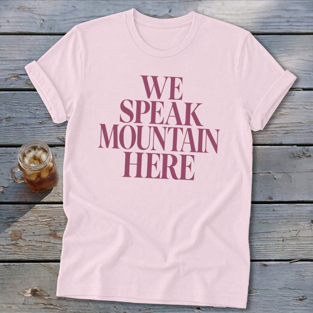 Pink t-shirt with "WE SPEAK MOUNTAIN HERE" text and a glass of iced tea.