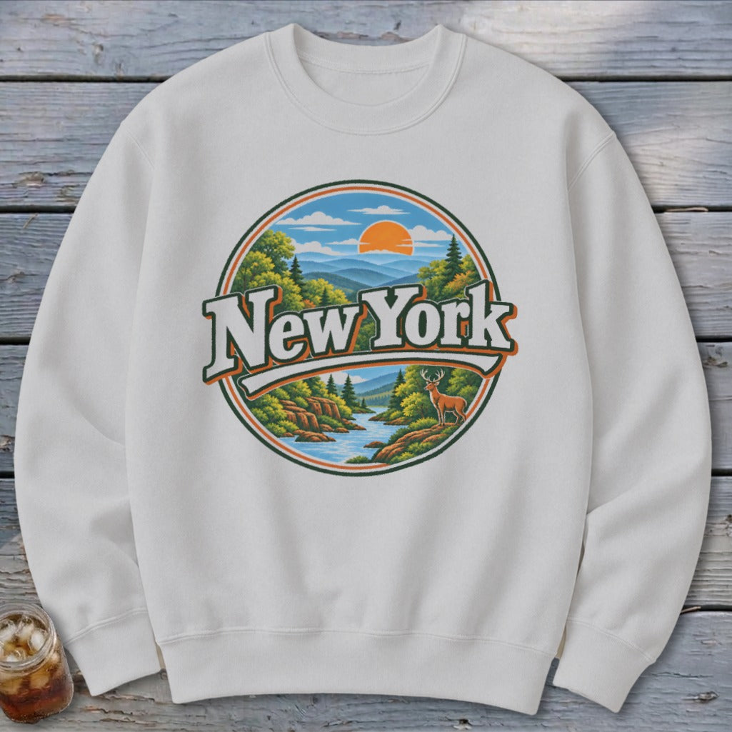 White sweatshirt with "New York" text over a scenic landscape design featuring mountains and a deer.