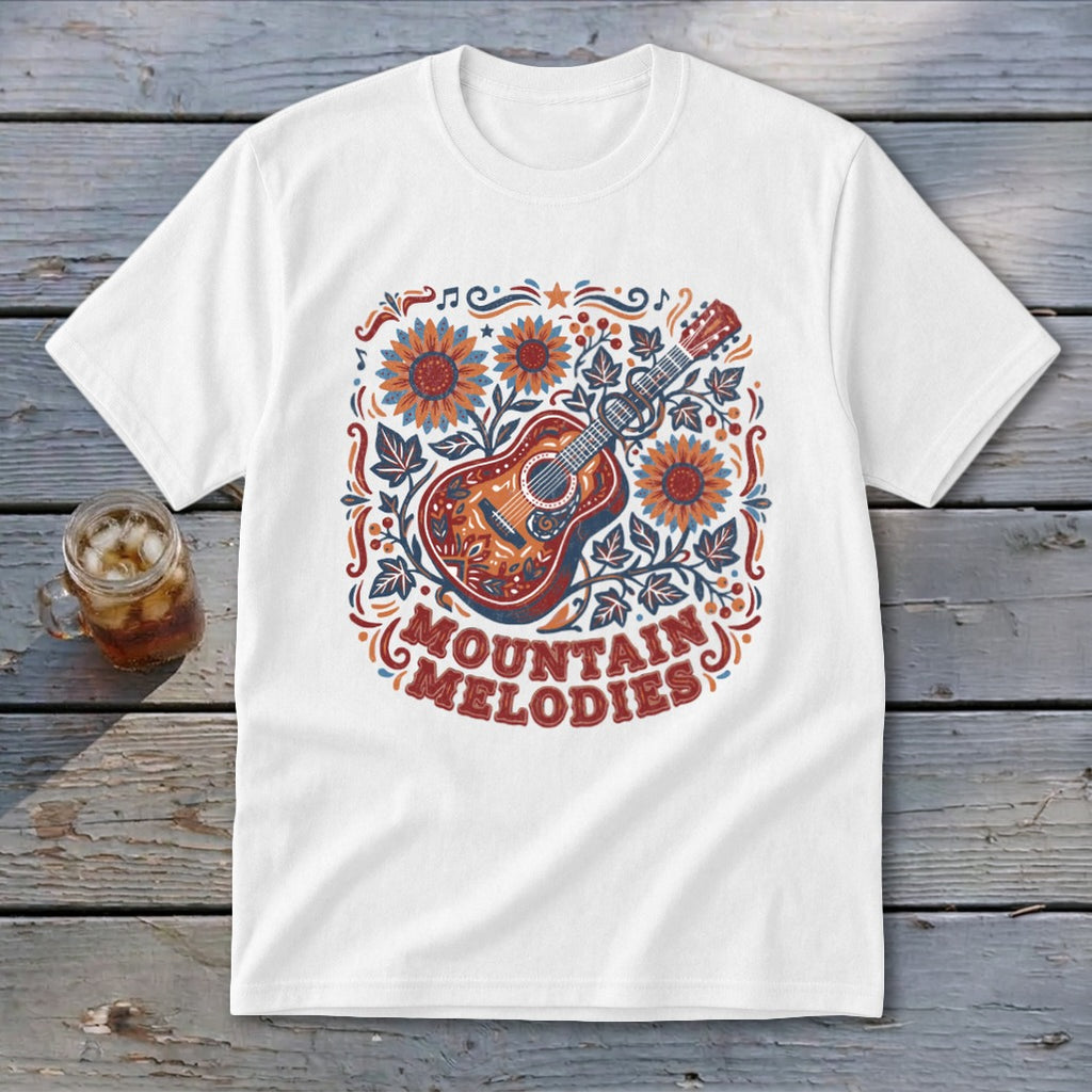 A white t-shirt featuring a colorful graphic of an acoustic guitar, sunflowers, leaves, and the text MOUNTAIN MELODIES.