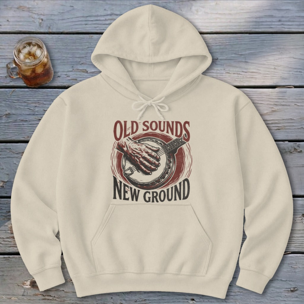 Beige hooded sweatshirt featuring a graphic of a hand playing a banjo and text reading Old Sounds New Ground.