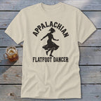 Light beige crewneck t-shirt featuring a black silhouette of a female dancer and Appalachian Flatfoot Dancer text on a wooden surface.