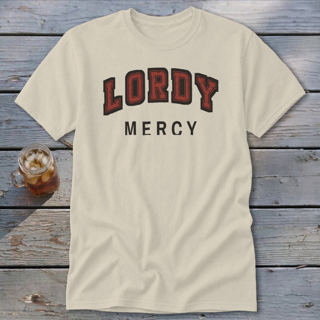 Cream t-shirt with red and black "LORDY MERCY" text on wooden background.
