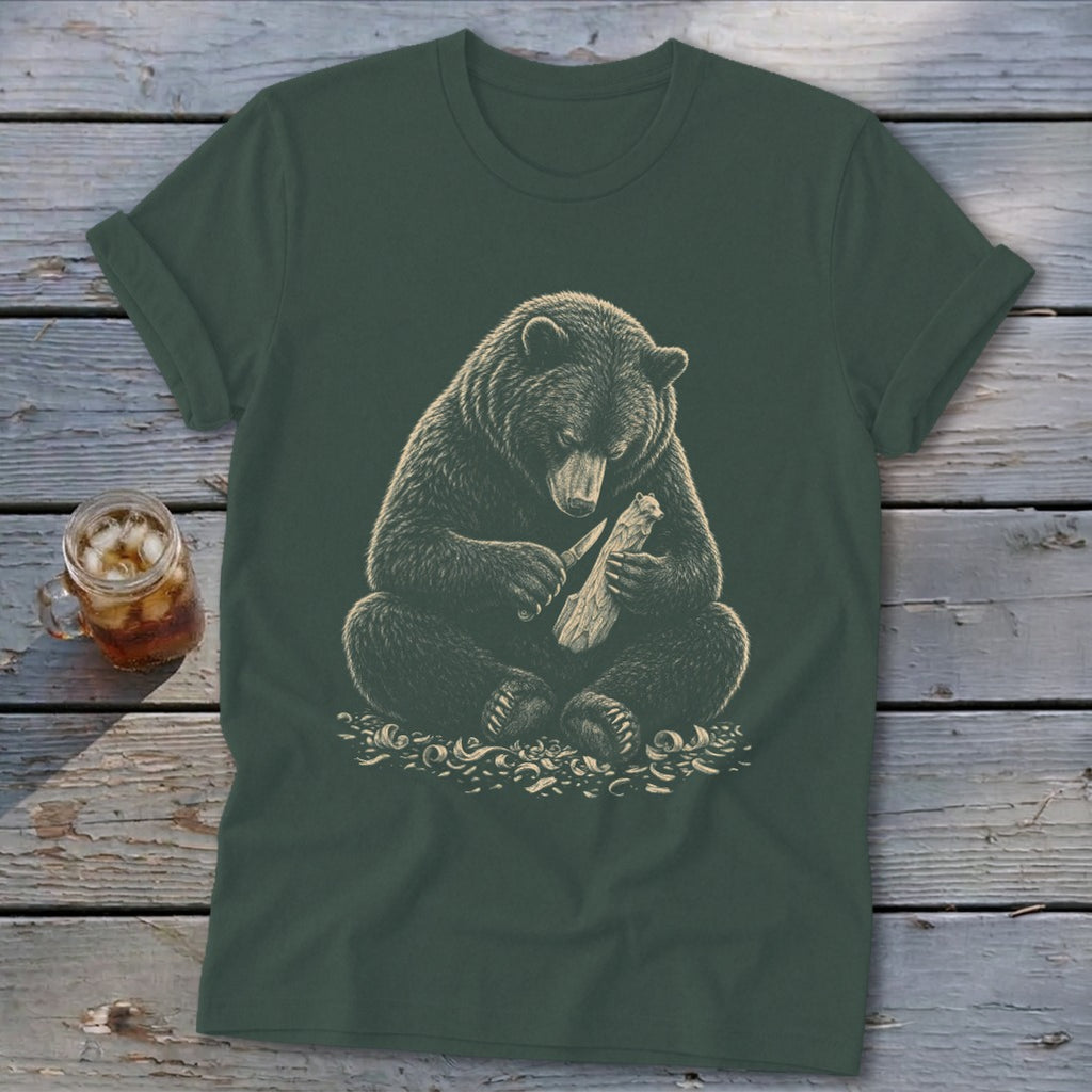 Bear carving wood with a knife on a dark green t-shirt.