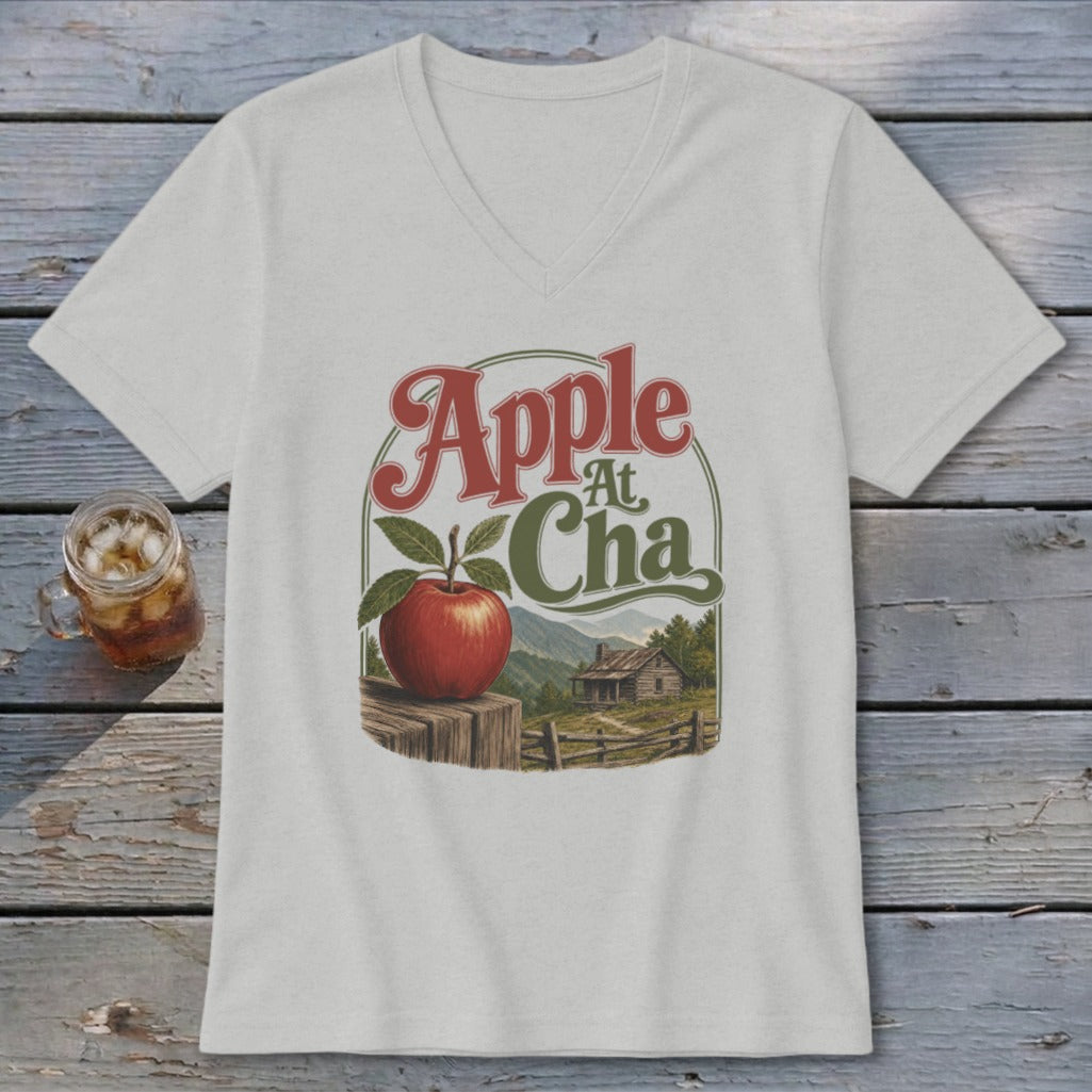 A light gray V-neck t-shirt with a graphic of an apple on a fence and mountains.