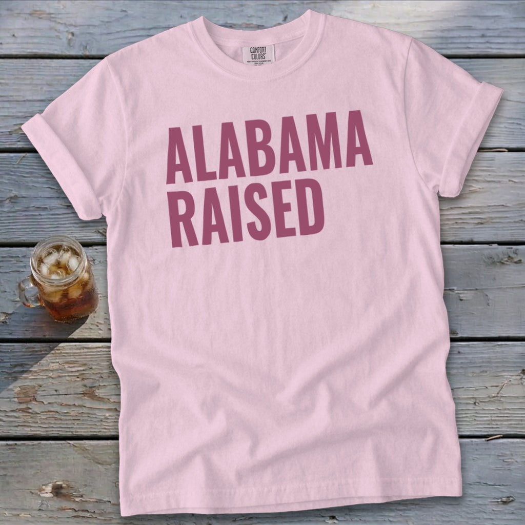 Pink t-shirt with "ALABAMA RAISED" printed in dark pink letters.