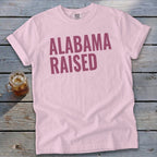 Pink t-shirt with "ALABAMA RAISED" printed in dark pink letters.