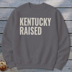 Grey sweatshirt with "KENTUCKY RAISED" text in off-white block letters.