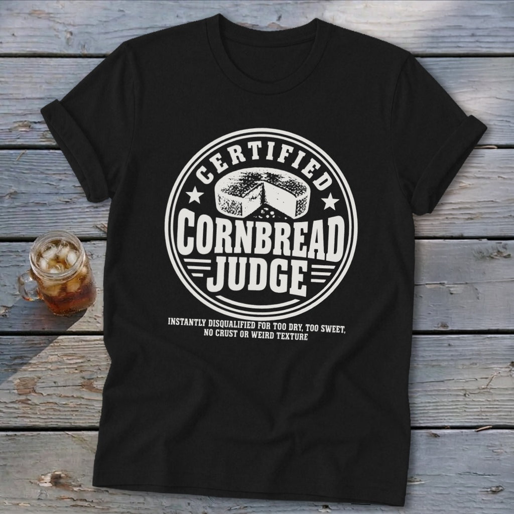 A black t-shirt with a white graphic that reads CERTIFIED CORNBREAD JUDGE with a cornbread illustration.