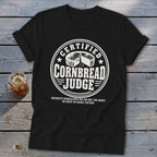 A black t-shirt with a white graphic that reads CERTIFIED CORNBREAD JUDGE with a cornbread illustration.