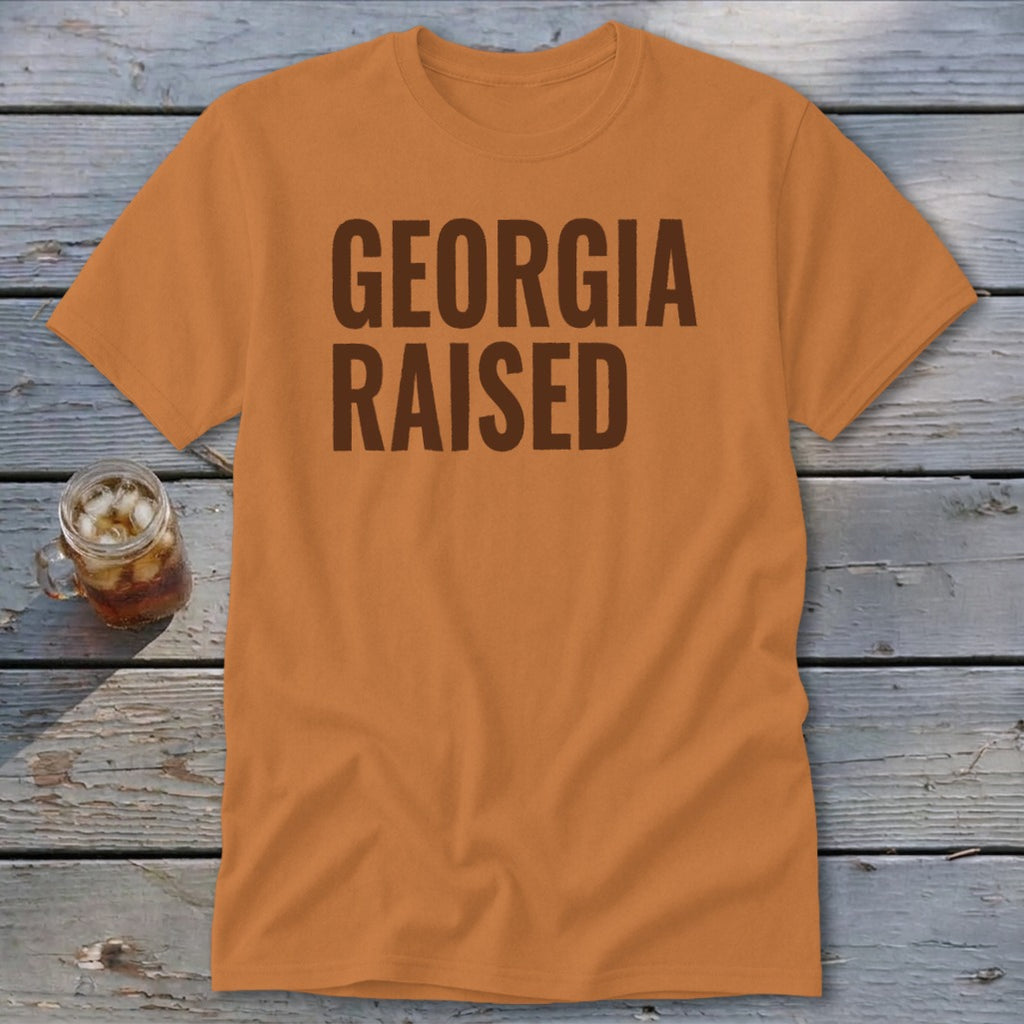 Orange t-shirt with "GEORGIA RAISED" text in brown, with a glass of iced tea.