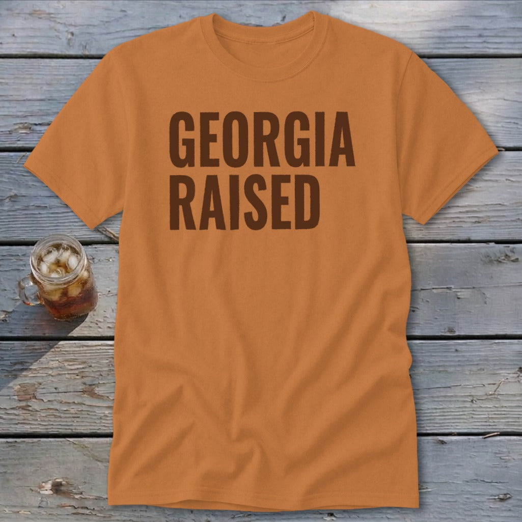 Orange t-shirt with "GEORGIA RAISED" text in brown, with a glass of iced tea.