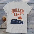 A light gray t-shirt with the orange text "HOLLER LIFE" and a mountain sunset graphic.