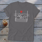 T-shirt graphic with line art of couple and dog on a swing with heart and mountains.
