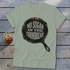 Light green t-shirt with a graphic of a cast iron skillet and the text "No Sugar In The Cornbread".