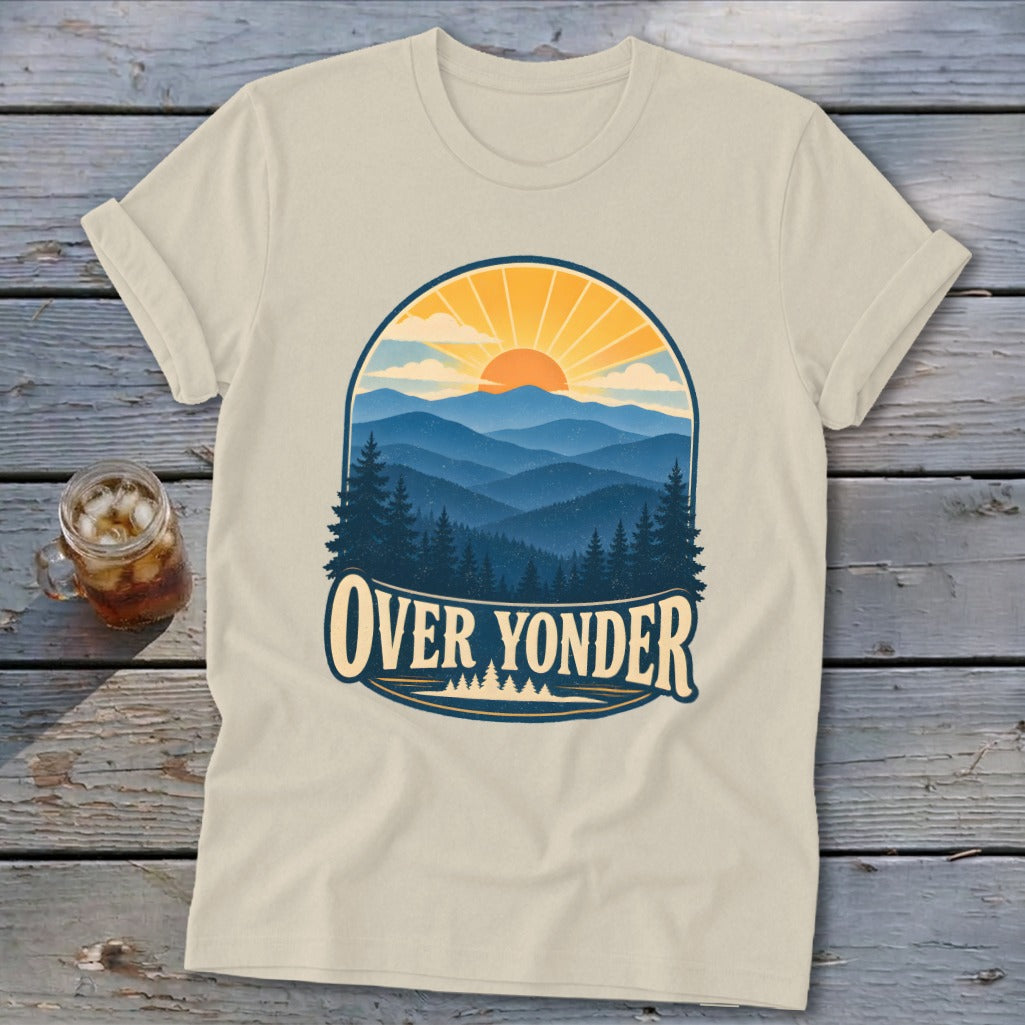 Beige t-shirt featuring a retro graphic of mountains, pine trees, a sunset, and the text Over Yonder.