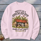 Sweatshirt with a spotted puppy sleeping under a red wagon.