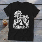 Black t-shirt with white graphic of farmhouse, trees, and text "OLD HOME PLACE".