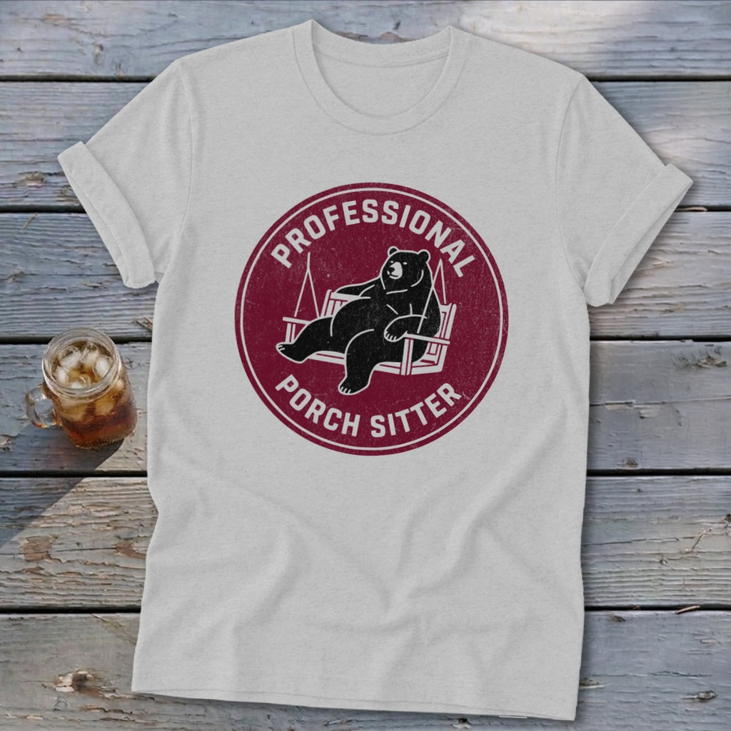 A light gray t-shirt featuring a circular maroon graphic of a bear lounging in a porch swing, surrounded by the text Professional Porch Sitter.