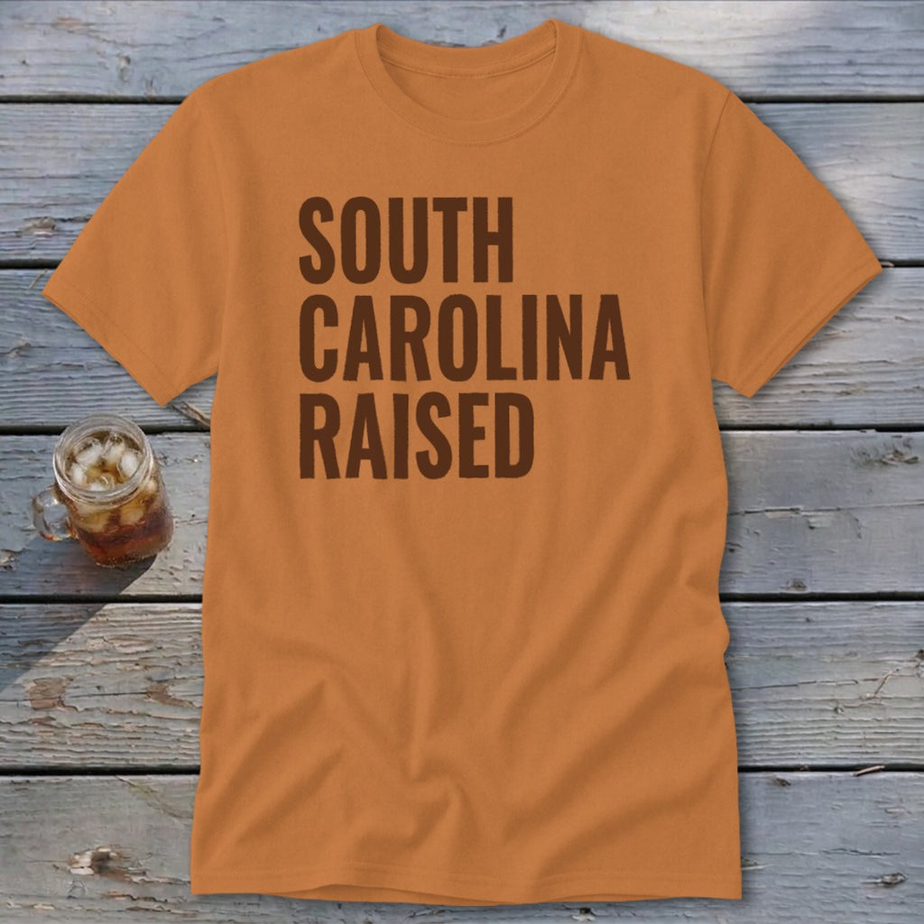 Orange t-shirt with brown text reading "SOUTH CAROLINA RAISED"