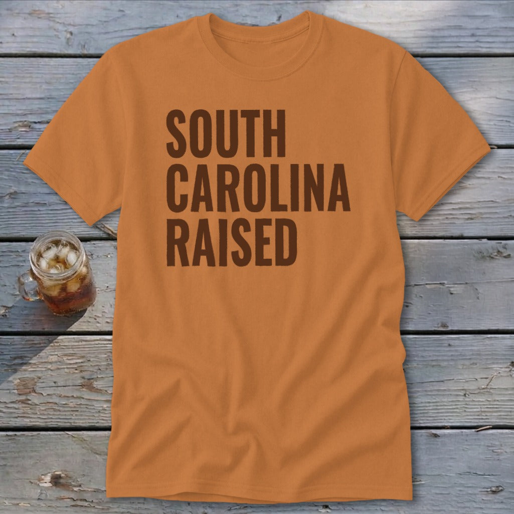 Orange t-shirt with brown text reading "SOUTH CAROLINA RAISED"