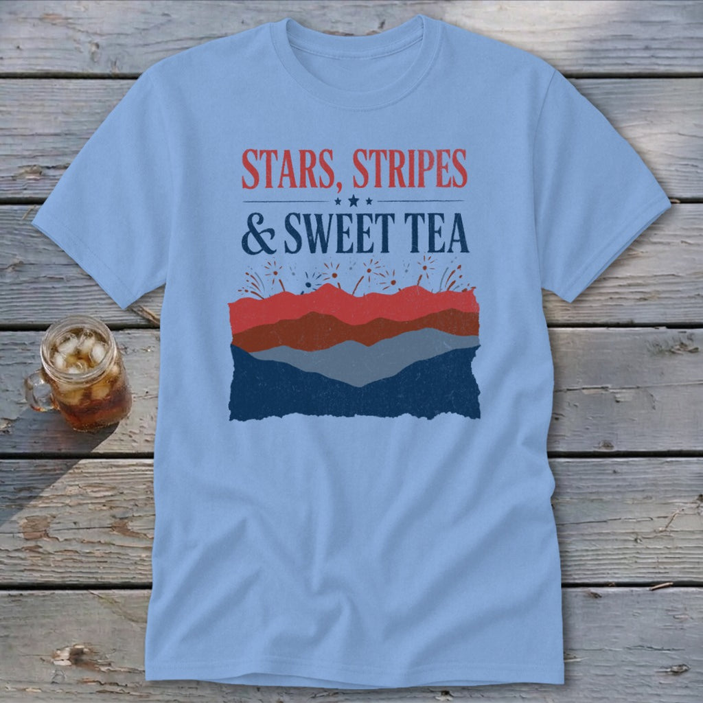 Light blue t-shirt featuring a graphic with the text Stars, Stripes & Sweet Tea laid over stylized red, white, and blue mountains.