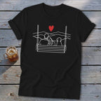 Black t-shirt with a white line drawing of a couple and dog on a swing with mountains.