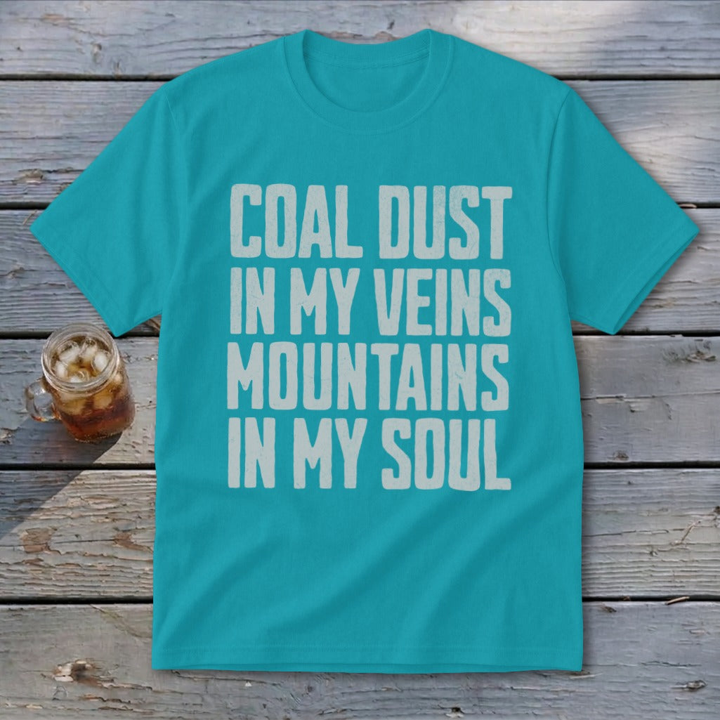 A teal t-shirt featuring the distressed white text COAL DUST IN MY VEINS MOUNTAINS IN MY SOUL.