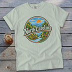 Light green t-shirt with a circular graphic of North Carolina mountains, river, and deer.