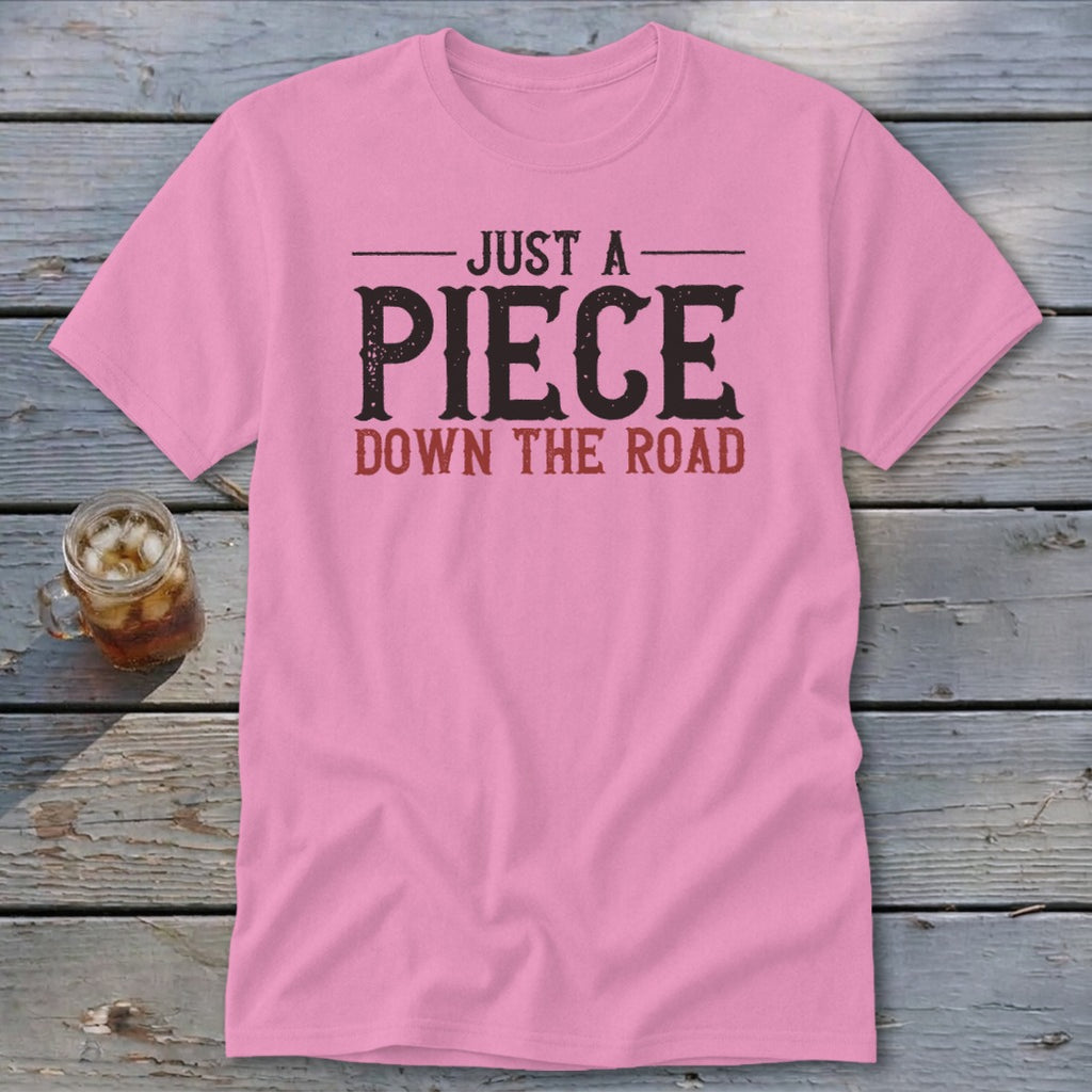 Pink t-shirt with "JUST A PIECE DOWN THE ROAD" text in black and red.