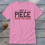 Pink t-shirt with "JUST A PIECE DOWN THE ROAD" text in black and red.