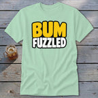Light green short-sleeve t-shirt with black-outlined yellow and white text reading BUM FUZZLED across the chest.