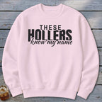 Pink sweatshirt with black text "THESE HOLLERS know my name".